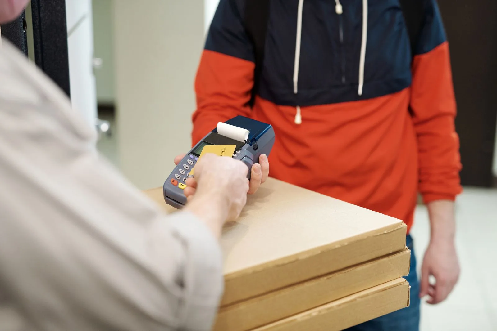 배달 기사가 차량 옆에서 모바일 단말기로 카드 결제를 받는 장면